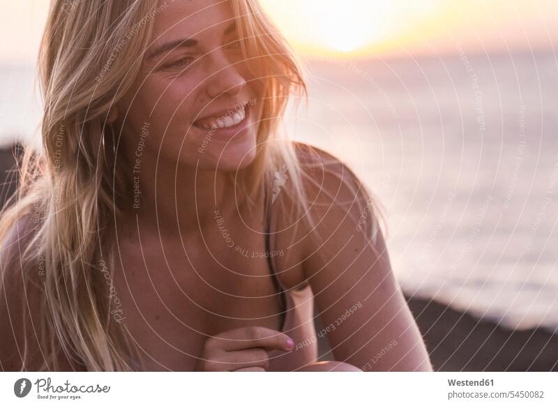 Spanien, Teneriffa, Porträt einer lachenden blonden Frau, die den Sonnenuntergang am Meer genießt Sonnenuntergänge genießen geniessen Genuss Portrait Porträts