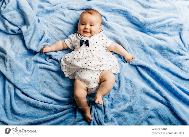 Bildnis eines lächelnden Mädchens auf einer hellblauen Decke liegend Baby Babies Babys Säuglinge Kind Kinder liegt Portrait Porträts Portraits Decken