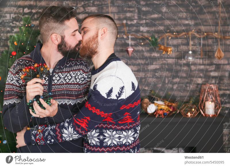 Homosexuelles Paar mit Lichterkette zur Weihnachtszeit zu Hause küssen Küsse Kuss Weihnachten Christmas X-Mas X mas Schwules Paar Schwuler Feste Festtag