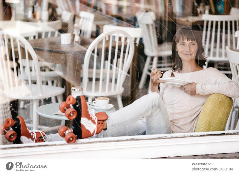 Frau auf Rollschuhen sitzt in einem Café und isst Kuchen weiblich Frauen essen essend sitzen sitzend Kaffee rollerskate rollerskates Cafe Kaffeehaus Bistro