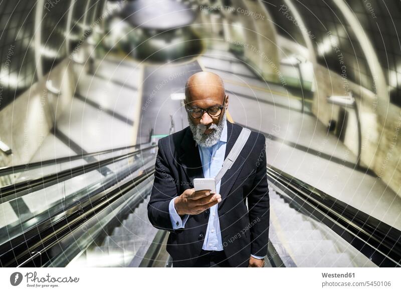 Geschäftsmann mit Smartphone liest Nachrichten auf Rolltreppe unterwegs auf Achse in Bewegung Mitteilung Botschaft lesen Lektüre SMS Textnachricht iPhone
