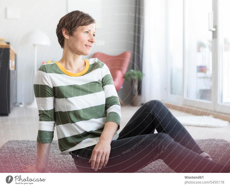 Porträt einer Frau, die im Wohnzimmer auf dem Boden sitzt sitzen sitzend weiblich Frauen Wohnraum Wohnung Wohnen Wohnräume Wohnungen Erwachsener erwachsen