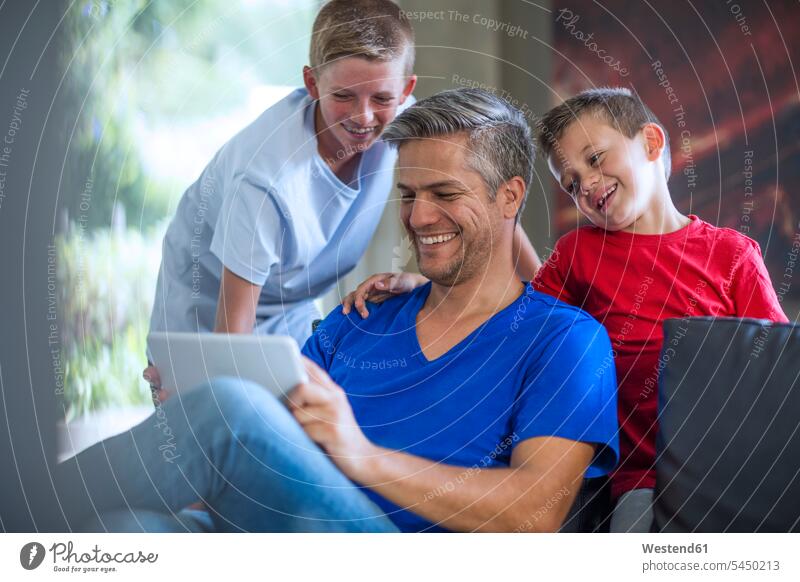 Kinder schauen mit ihrem Vater auf ein digitales Tablett lachen Tablet Computer Tablet-PC Tablet PC iPad Tablet-Computer Zuhause zu Hause daheim Familie