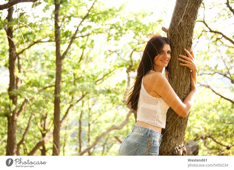 Junge Frau im Wald umarmt einen Baum Bäume Baeume umarmen Umarmung Umarmungen Arm umlegen lächeln weiblich Frauen Erwachsener erwachsen Mensch Menschen Leute