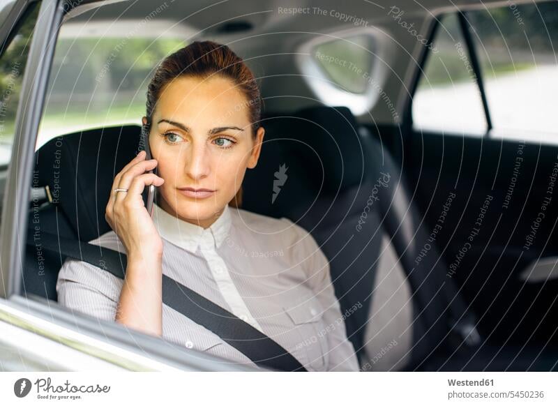Geschäftsfrau am Telefon, die auf dem Rücksitz eines Autos sitzt Geschäftsfrauen Businesswomen Businessfrauen Businesswoman Wagen PKWs Automobil Portrait