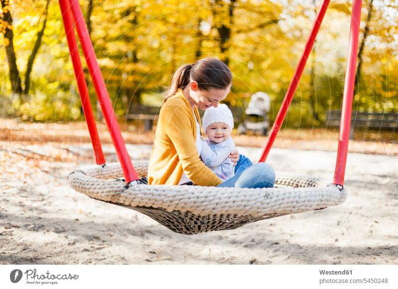 Glückliches kleines Mädchen entspannt sich im Herbst mit seiner Mutter auf einer Schaukel glücklich glücklich sein glücklichsein Spielplatz Spielplätze