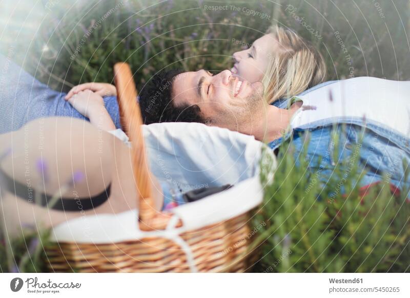 Junges Paar im Lavendelfeld liegend Pärchen Paare Partnerschaft lächeln entspannt entspanntheit relaxt Mensch Menschen Leute People Personen Entspannung relaxen