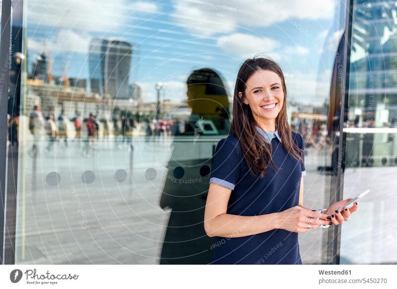 UK, London, Porträt einer lächelnden Frau mit Smartphone in der Stadt weiblich Frauen Handy Mobiltelefon Handies Handys Mobiltelefone Erwachsener erwachsen
