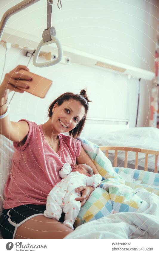Mutter macht ein Selfie mit ihrem neugeborenen Baby im Krankenhausbett Selfies Mami Mutti Mütter Mama Eltern Familie Familien Mensch Menschen Leute People