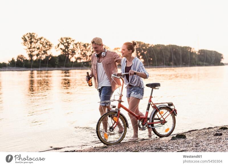 Junges Paar mit Fahrrad watend im Fluss lächeln gehen gehend geht Pärchen Paare Partnerschaft Mensch Menschen Leute People Personen Fluesse Fluß Flüsse Gewässer