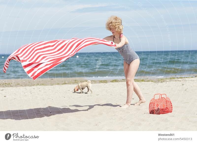 Junge Frau mit wehendem Strandtuch am Meer Beach Straende Strände Beaches weiblich Frauen Erwachsener erwachsen Mensch Menschen Leute People Personen Wind