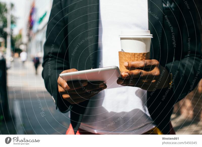 USA, NYC, Brooklyn, Mann geht auf der Straße mit einer Tasse Kaffee und einem digitalen Tablett in der Hand Männer männlich Tablet Computer Tablet-PC Tablet PC