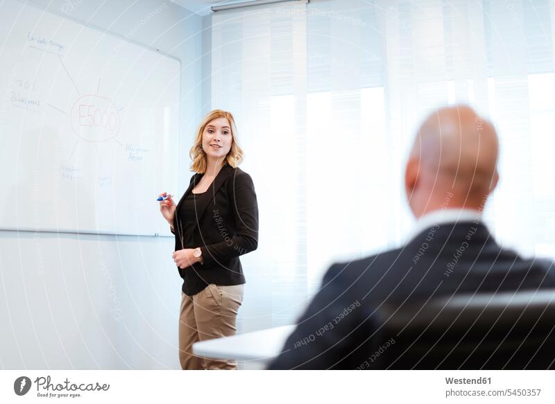 Geschäftsmann betrachtet Geschäftsfrau am Whiteboard im Büro Geschäftsfrauen Businesswomen Businessfrauen Businesswoman schreiben aufschreiben notieren