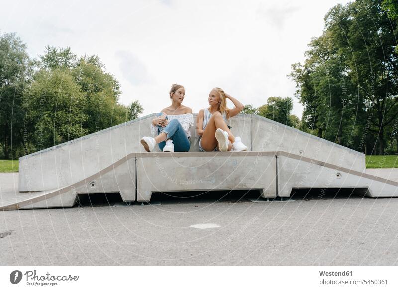 Zwei junge Frauen unterhalten sich in einem Skatepark Freundinnen Skateboardpark Skateboard-Park Skateboard Park Skaterplatz weiblich Parkanlagen Parks sprechen