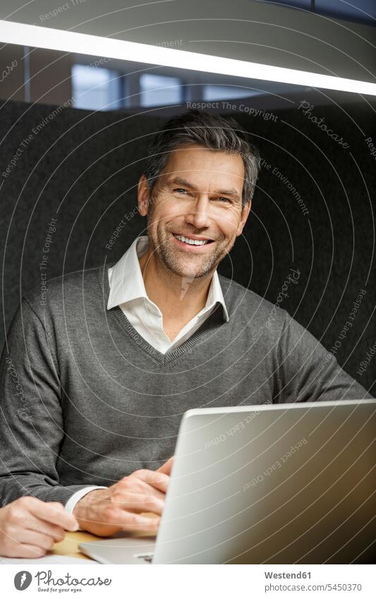 Porträt eines lächelnden Geschäftsmannes mit Laptop in einer Besprechungskiste Büro Office Büros Portrait Porträts Portraits Notebook Laptops Notebooks