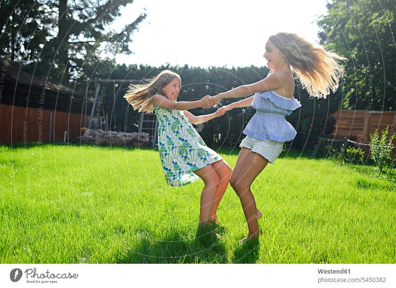 Zwei fröhlich verspielte Mädchen im Garten Freundinnen spielen glücklich Glück glücklich sein glücklichsein Gärten Gaerten drehen weiblich Freunde Freundschaft