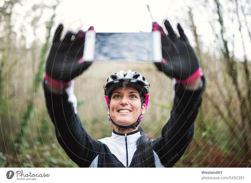 Lächelnde Mountainbikerin macht ein Selfie Selfies Frau weiblich Frauen lächeln Fahrradhelm Radhelm Fahrradhelme Mountainbiking mountainbiken MTB Handy