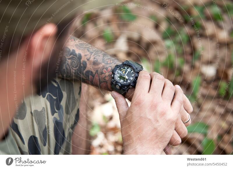 Nahaufnahme eines Mannes im Wald bei der Zeitkontrolle Armbanduhr Armbanduhren Tattoo Tätowierungen Tatoos Taetowierung Tattoos Taetowierungen Männer männlich