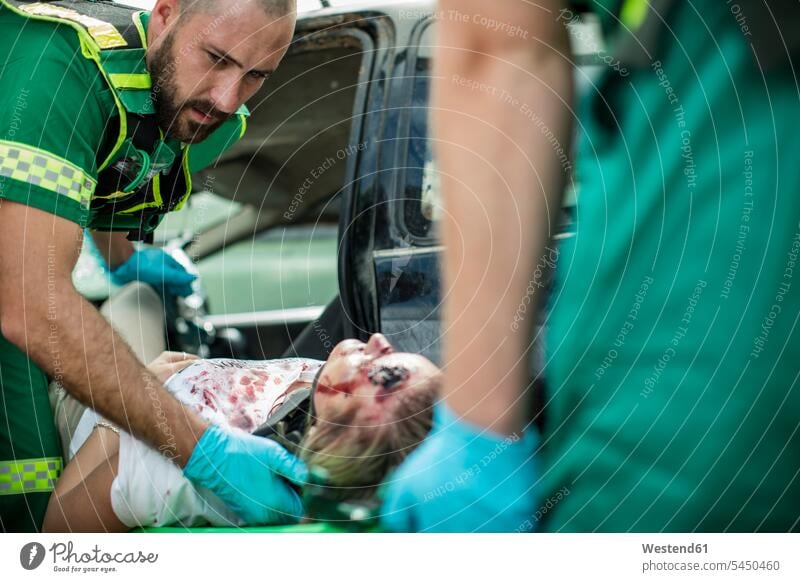 Sanitäter bewegen Autounfallopfer auf Bahre transportieren tragen Trage Tragbahre Bahren Tragen Krankenliegen Tragbahren Unfall Verletzung verletzt Verletzungen