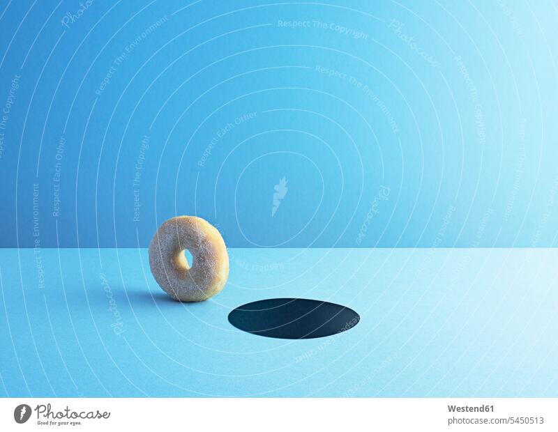 Doughnut und Loch auf hellblauem Grund Einzelner Gegenstand 1 Einzelgegenstand ein ein Gegenstand einzeln Backwaren rollen rollend blauer Hintergrund