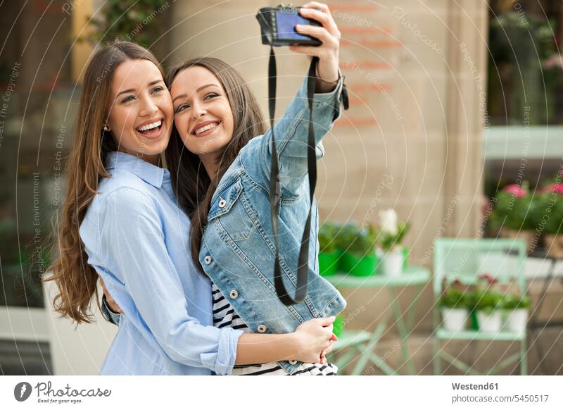 Lachende Freundinnen machen ein Selfie auf der Straße Selfies fotografieren lachen Fotoapparat Kamera Fotokamera Gemeinsam Zusammen Miteinander positiv Emotion