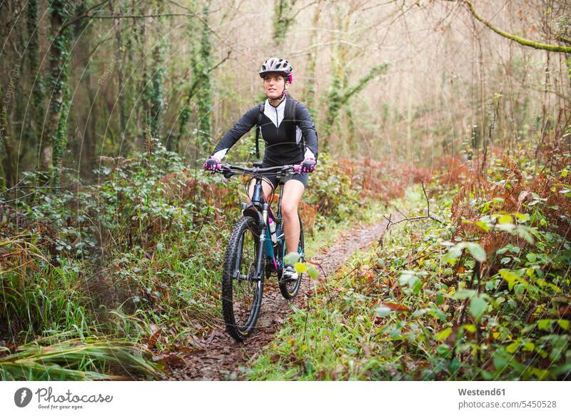 Mountainbikerin fährt mit ihrem Fahrrad auf einem Waldweg Mountainbiking mountainbiken MTB Mountainbikes fahren Frau weiblich Frauen Radsport Sport Bikes