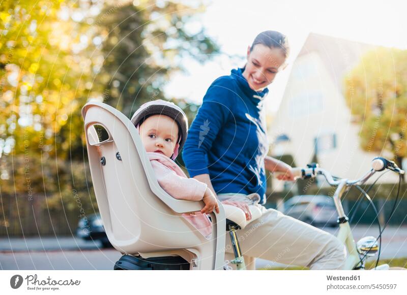 Mutter und Tochter fahren Fahrrad, das Baby trägt einen Helm und sitzt im Kindersitz Bikes Fahrräder Räder Rad radfahren fahrradfahren radeln Fahrradhelm