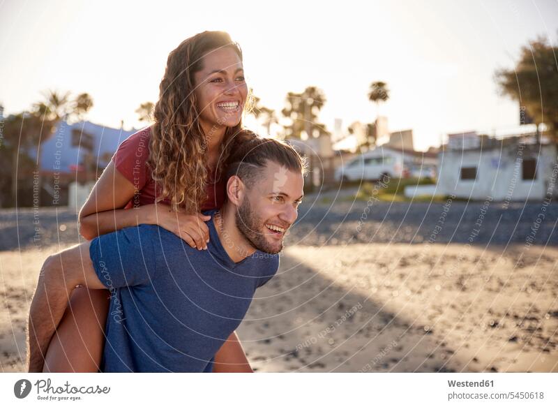 Junger Mann reitet seine Freundin am Strand Huckepack Paar Pärchen Paare Partnerschaft Beach Straende Strände Beaches Mensch Menschen Leute People Personen
