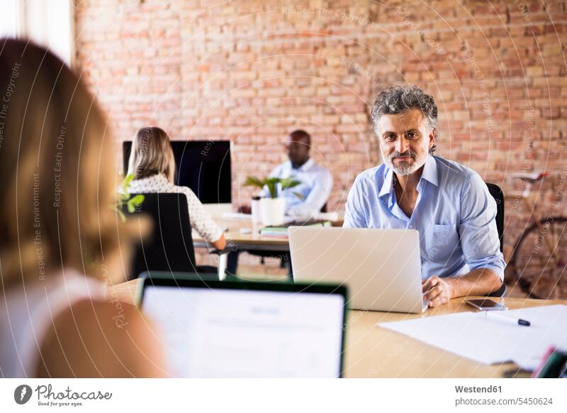 Porträt eines selbstbewussten Geschäftsmannes im Amt mit Kollegen im Hintergrund Büro Office Büros Laptop Notebook Laptops Notebooks arbeiten Arbeit