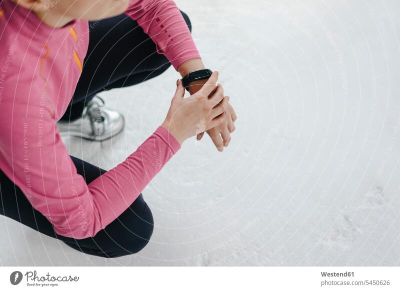 Frau in Sportkleidung kauerndes Aktivitätsband tragend Activity Tracker Fitness Tracker Smart Band Aktivitätsarmband Aktivitätstracker Fitness-Tracker