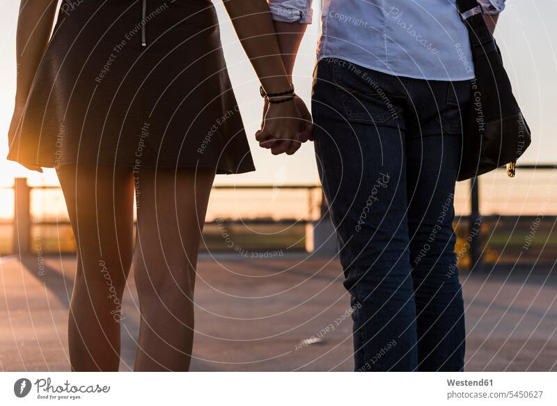 Junges Paar Hand in Hand auf Parkebene bei Sonnenuntergang Sonnenuntergänge Parkdeck Parkdecks Pärchen Paare Partnerschaft Stimmung stimmungsvoll Atmosphäre