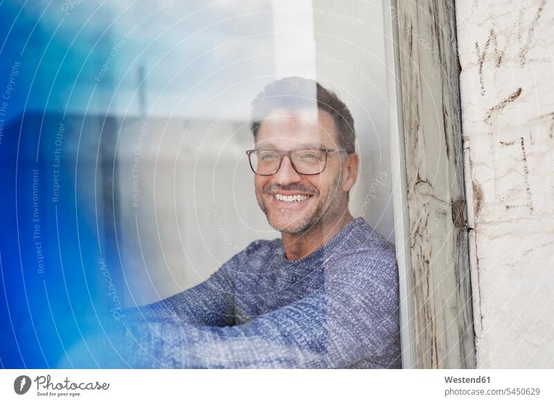 Porträt eines lachenden Mannes hinter Glasscheibe mit Brille Männer männlich Portrait Porträts Portraits Brillen Fenster Glasscheiben Erwachsener erwachsen