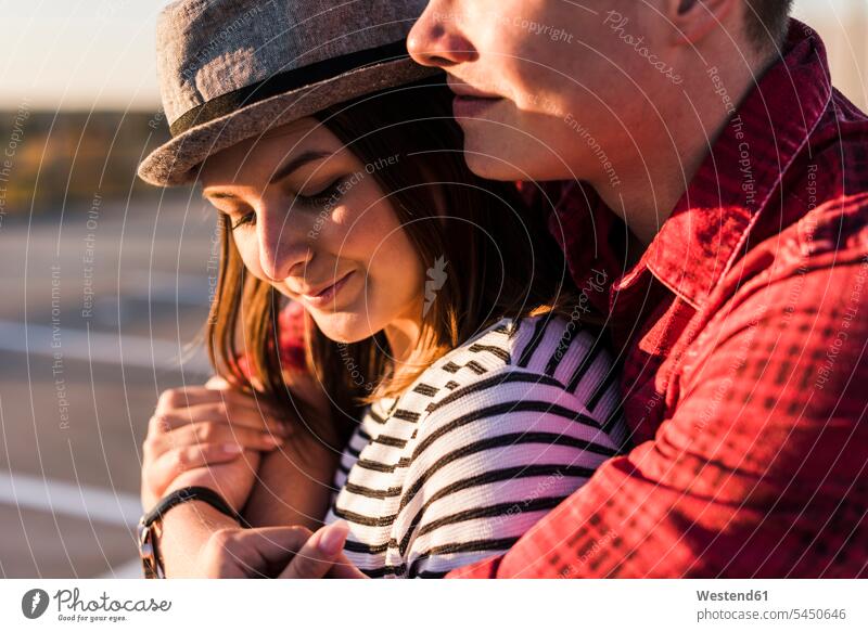 Nahaufnahme eines jungen Paares, das sich bei Sonnenuntergang umarmt Sonnenuntergänge umarmen Umarmung Umarmungen Arm umlegen Pärchen Partnerschaft Stimmung