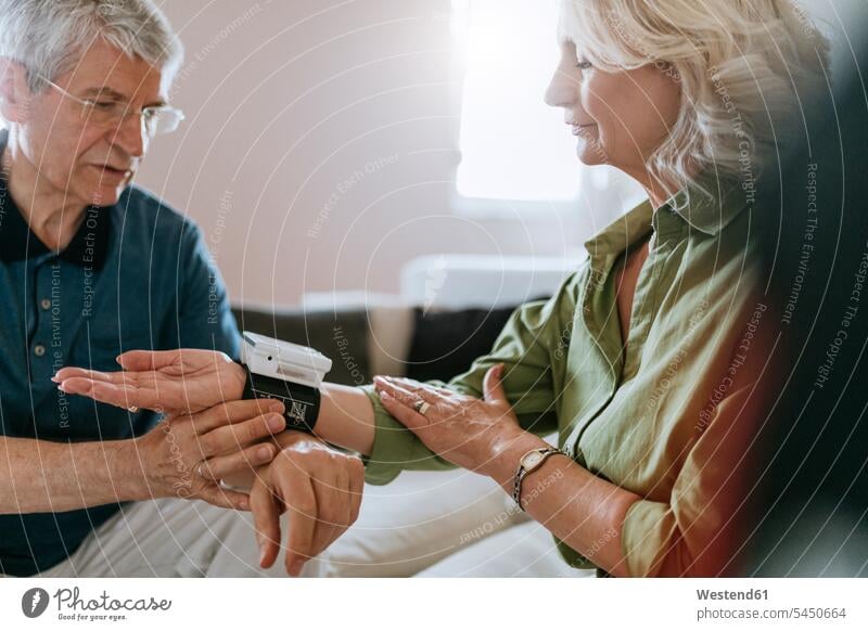 Älteres Ehepaar, das seinen Blutdruck zu Hause misst Senior ältere Männer älterer Mann Senioren Paar Pärchen Paare Partnerschaft männlich Erwachsener erwachsen