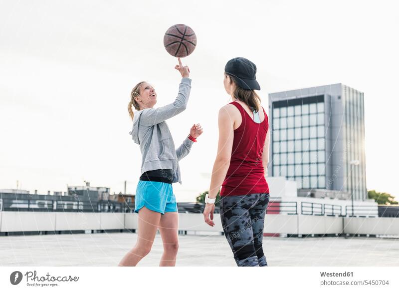 Frau dreht Basketball auf einem Parkdeck in der Stadt Basketbaelle Basketbälle lächeln weiblich Frauen Freundinnen Sport Erwachsener erwachsen Mensch Menschen