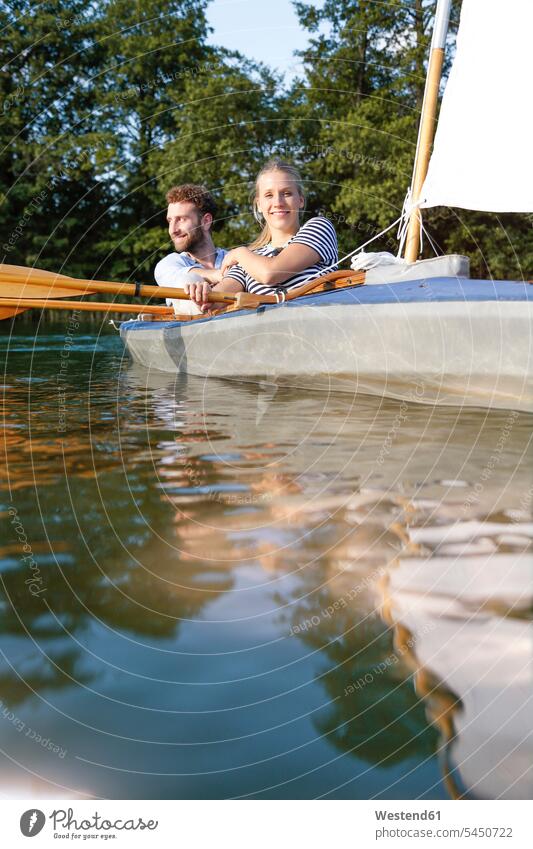 Junges Paar geniesst eine Kanufahrt mit Segeln auf einem See genießen geniessen Genuss Seen Kanus Pärchen Paare Partnerschaft Ausflug Ausflüge Kurzurlaub