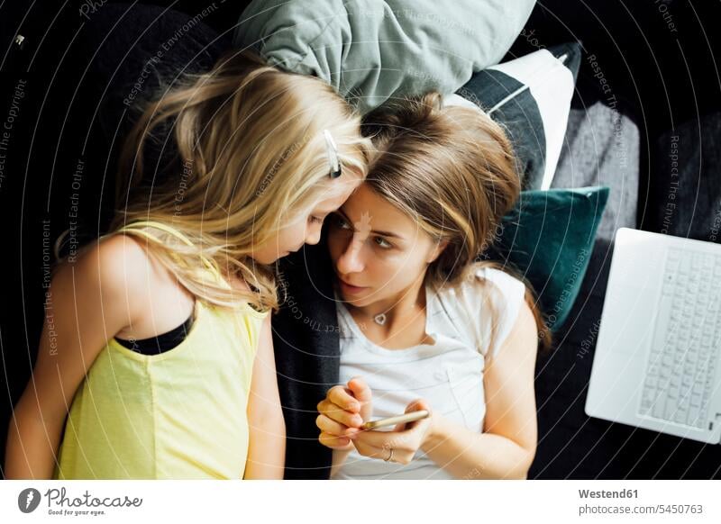 Entspannte Mutter und Tochter mit Handy auf dem Sofa Zuhause zu Hause daheim Mobiltelefon Handies Handys Mobiltelefone entspannt entspanntheit relaxt Mami Mutti