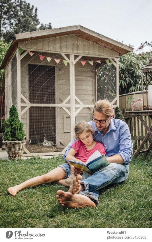 Vater liest Buch mit Tochter im Garten lesen Lektüre Bücher entspannt entspanntheit relaxt Töchter Gärten Gaerten Papas Väter Vati Vatis Papis Entspannung