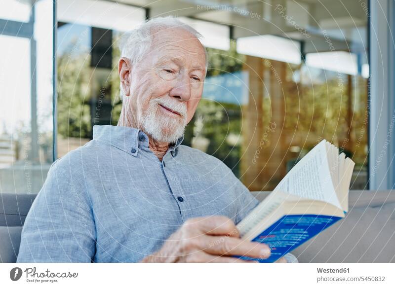 Älterer Mann sitzt auf der Terrasse und liest Buch Terrassen Bücher sitzen sitzend Rentner Pensionär Pensionäre lesen Lektüre Senior ältere Männer älterer Mann