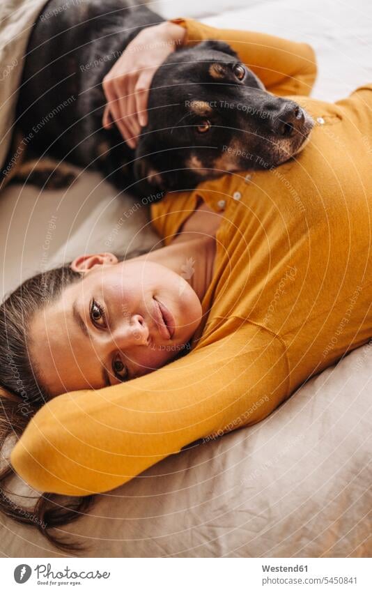 Frau liegt mit ihrem Hund im Bett weiblich Frauen tierlieb Tierliebe Hunde liegen liegend Betten kuscheln schmusen knuddeln umarmen Umarmung Umarmungen