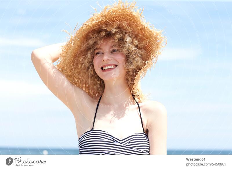 Porträt einer glücklichen jungen Frau mit Strohhut am Strand weiblich Frauen Hut Hüte Portrait Porträts Portraits Erwachsener erwachsen Mensch Menschen Leute