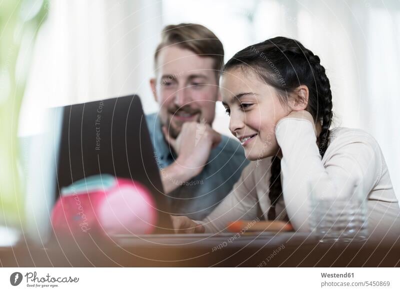 Vater und Tochter schauen gemeinsam auf den Laptop lächeln lernen Kind Familie Mensch Computer Eltern WLan Laptop benutzen Tisch E-Learning