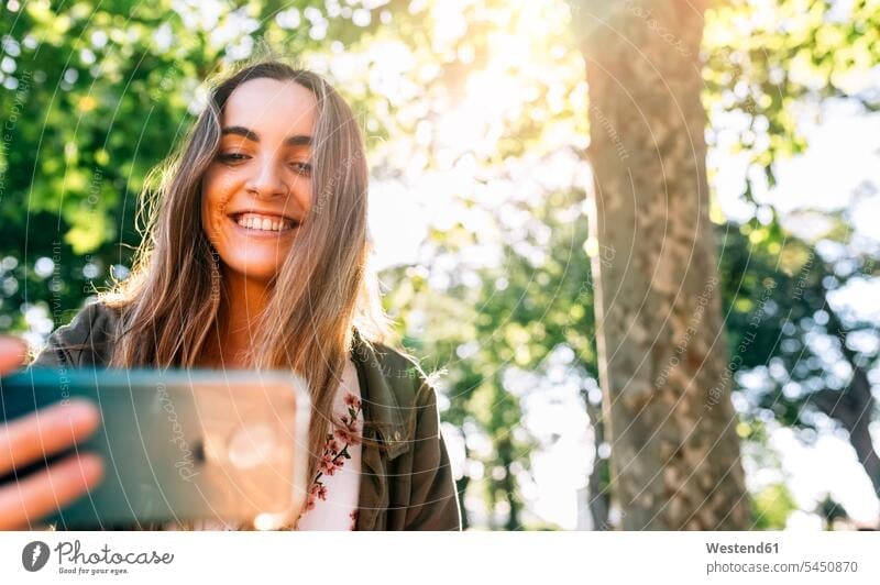 Glückliche junge Frau mit Smartphone-Türen Portrait Porträts Portraits lächeln glücklich glücklich sein glücklichsein Handy Mobiltelefon Handies Handys