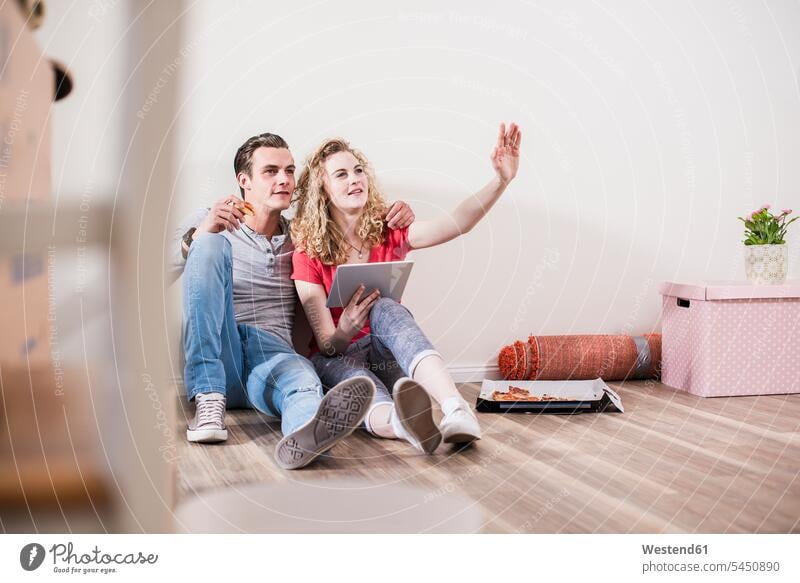 Junges Paar in neuer Wohnung sitzt mit Tablette auf dem Boden Pärchen Paare Partnerschaft wohnen Wohnungen Mensch Menschen Leute People Personen Wohnen