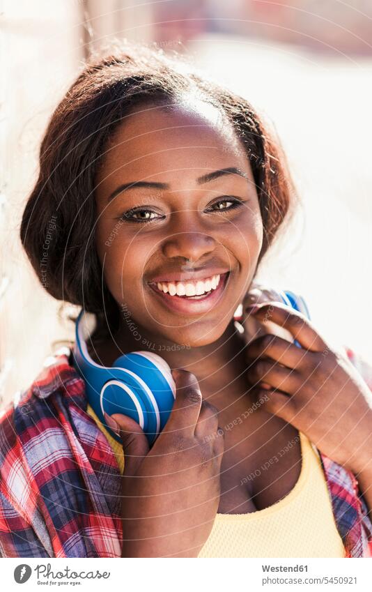 Porträt einer glücklichen jungen Frau mit Kopfhörern um den Hals fröhlich Fröhlichkeit Frohsinn Heiterkeit Glück glücklich sein glücklichsein Portrait Porträts