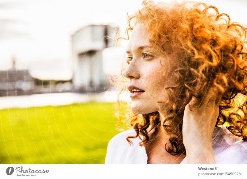 Deutschland, Köln, Porträt einer sommersprossigen jungen Frau mit lockigem roten Haar Portrait Porträts Portraits weiblich Frauen Locken lockiges Haar gelockt