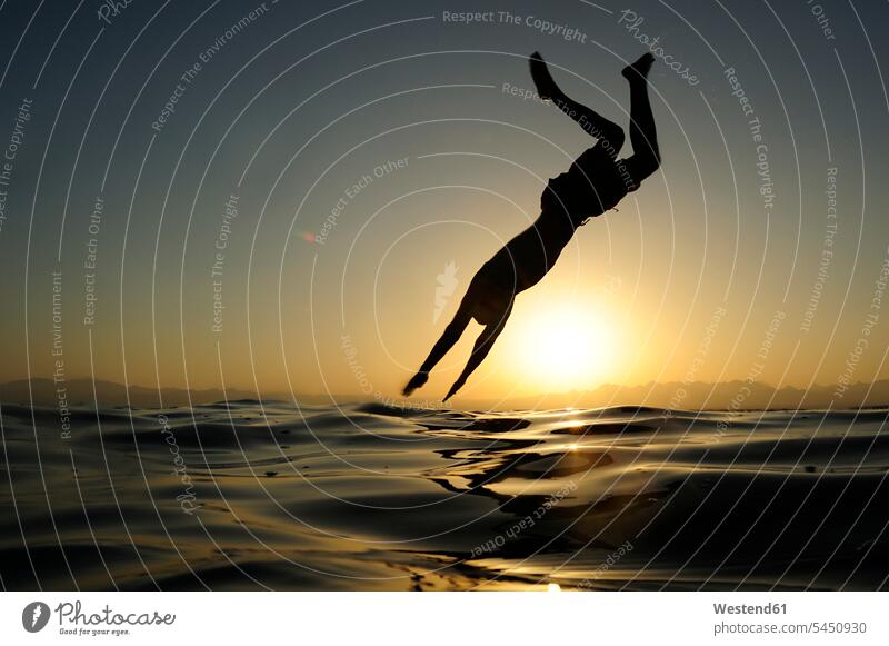 Mann springt bei Sonnenuntergang ins Meer springen hüpfen Männer männlich Meere Urlaub Ferien Sprung Spruenge Sprünge Erwachsener erwachsen Mensch Menschen