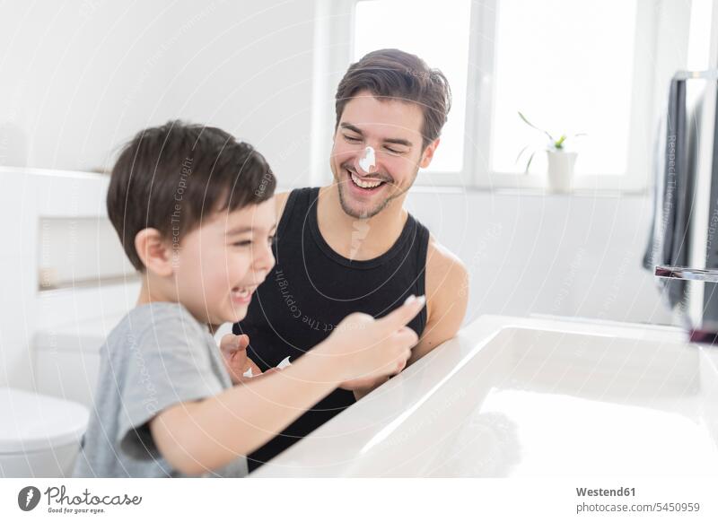 Verspielter Sohn trägt Rasierschaum auf die Nase des Vaters auf Spaß Spass Späße spassig Spässe spaßig anwenden auftragen Papas Väter Vati Vatis Papis lachen