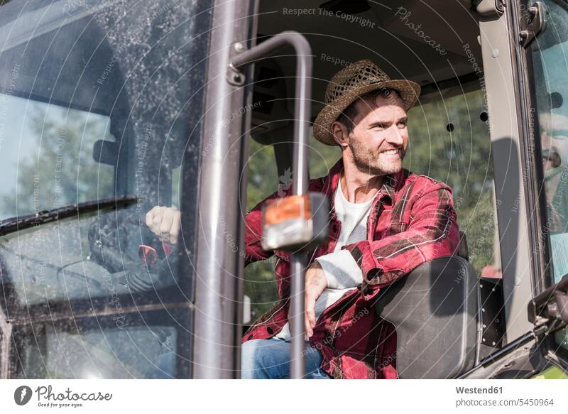 Lächelnder Landwirt auf dem Traktor Mann Männer männlich lächeln Bauer Landwirte Bauern Schlepper Traktoren Trecker Erwachsener erwachsen Mensch Menschen Leute