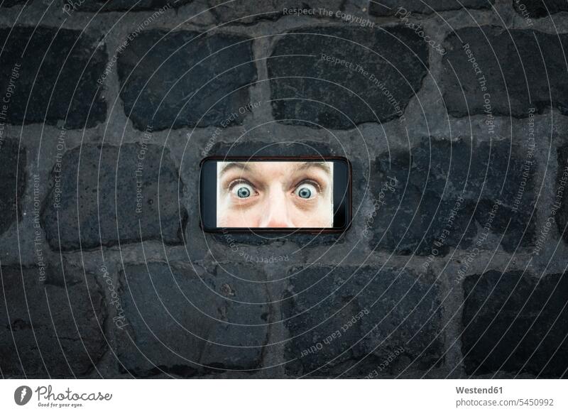 Bild eines Mobiltelefons mit weit geöffneten Augen auf Kopfsteinpflaster Menschliche Augen Foto Fotos Pflasterstein Pflastersteine Handy Handies Handys